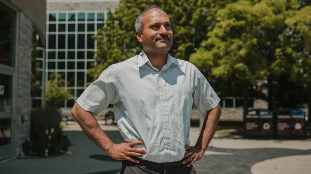 Ravi Selvaganapathy stands outside JHE with hands on his hips looking off into the distance