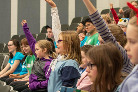 Kids in a classroom raising hands