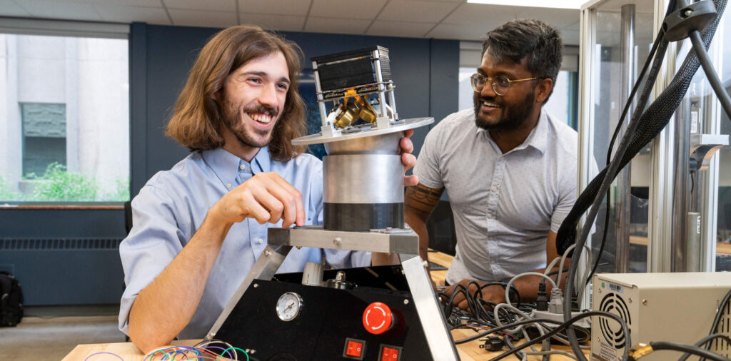 Two students work on machinery in Dr. Andrew Gadsden's lab.