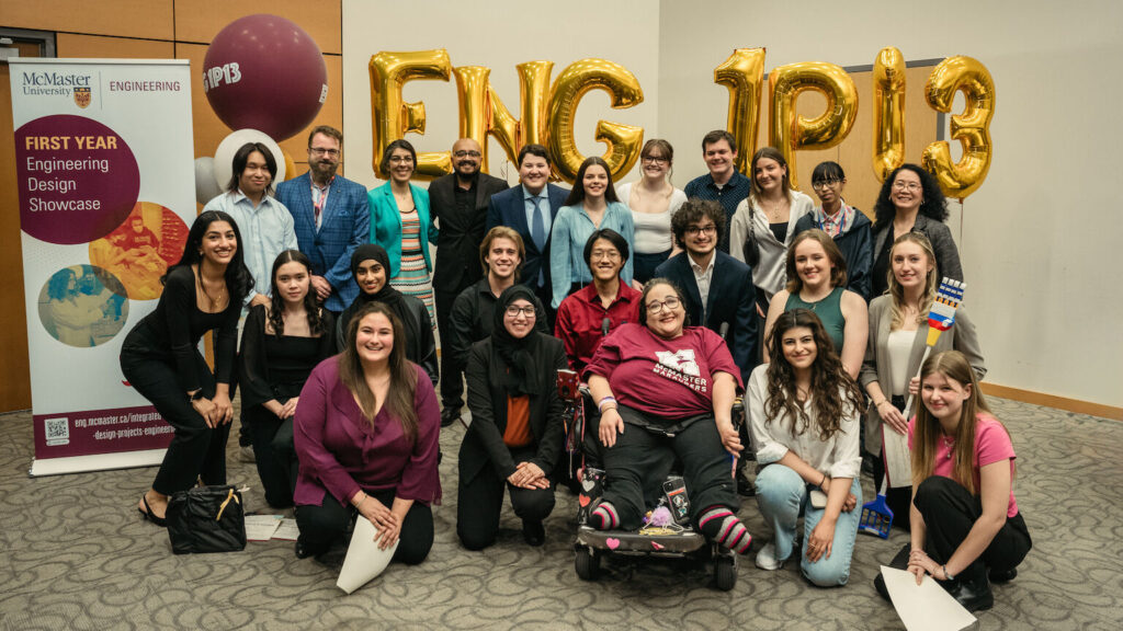 group picture of people posing in front of gold foil balloons.