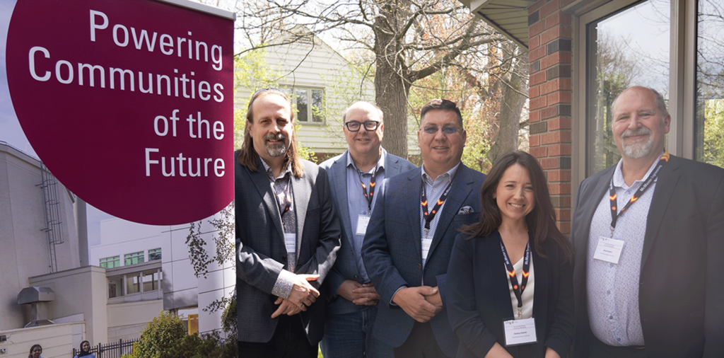 A group of people standing outside next to a Powering Communities of the Future sign