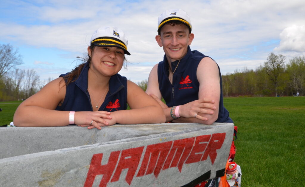 two people posing in captain hats, learning on the edge of a concrete canoe.