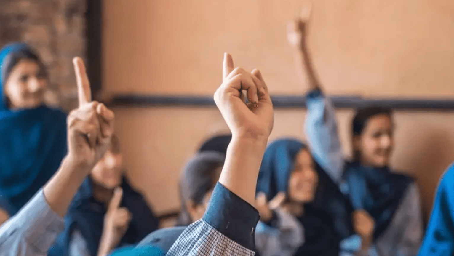a classroom of girls with their hands up in the air.