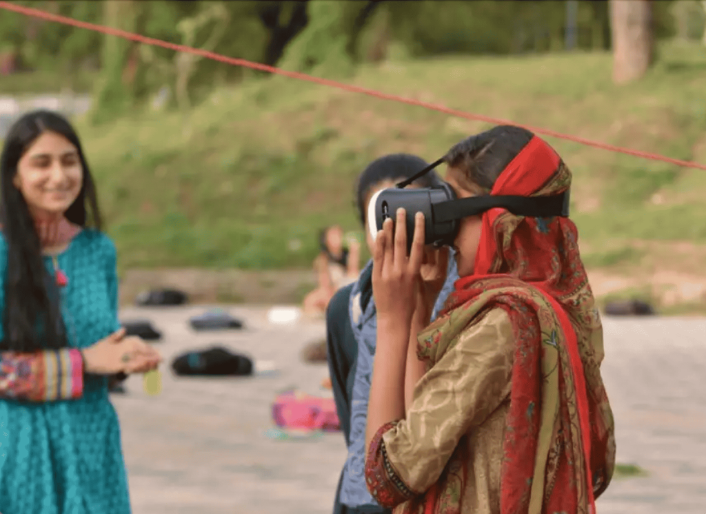 young girls playing outside, one is wearing a VR headset.
