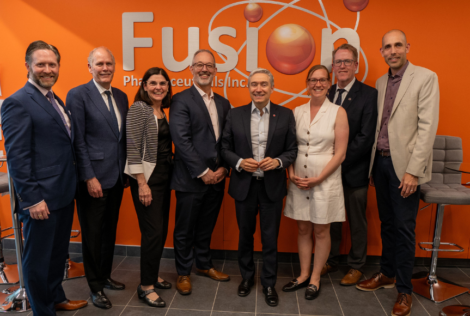 McMaster researchers and external guests standing in front of a Fusion sign on campus