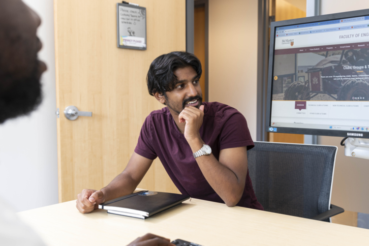 Student looking at computer screen with hand on chin