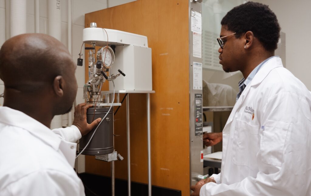 a professor showing a graduate student how to use a machine in a lab.