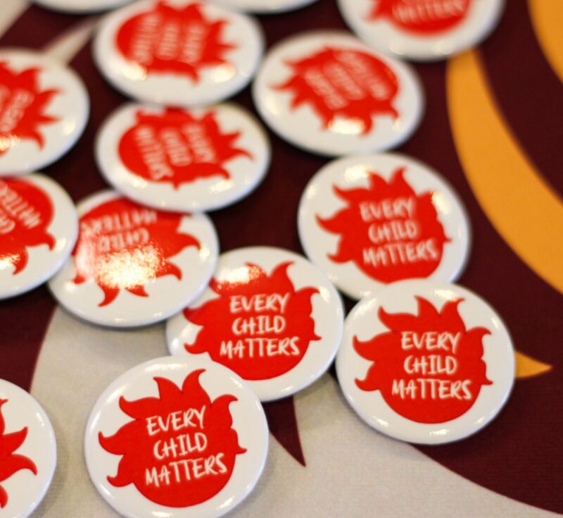 A pile of buttons. Each button says 'every child matters' on a fireball logo.