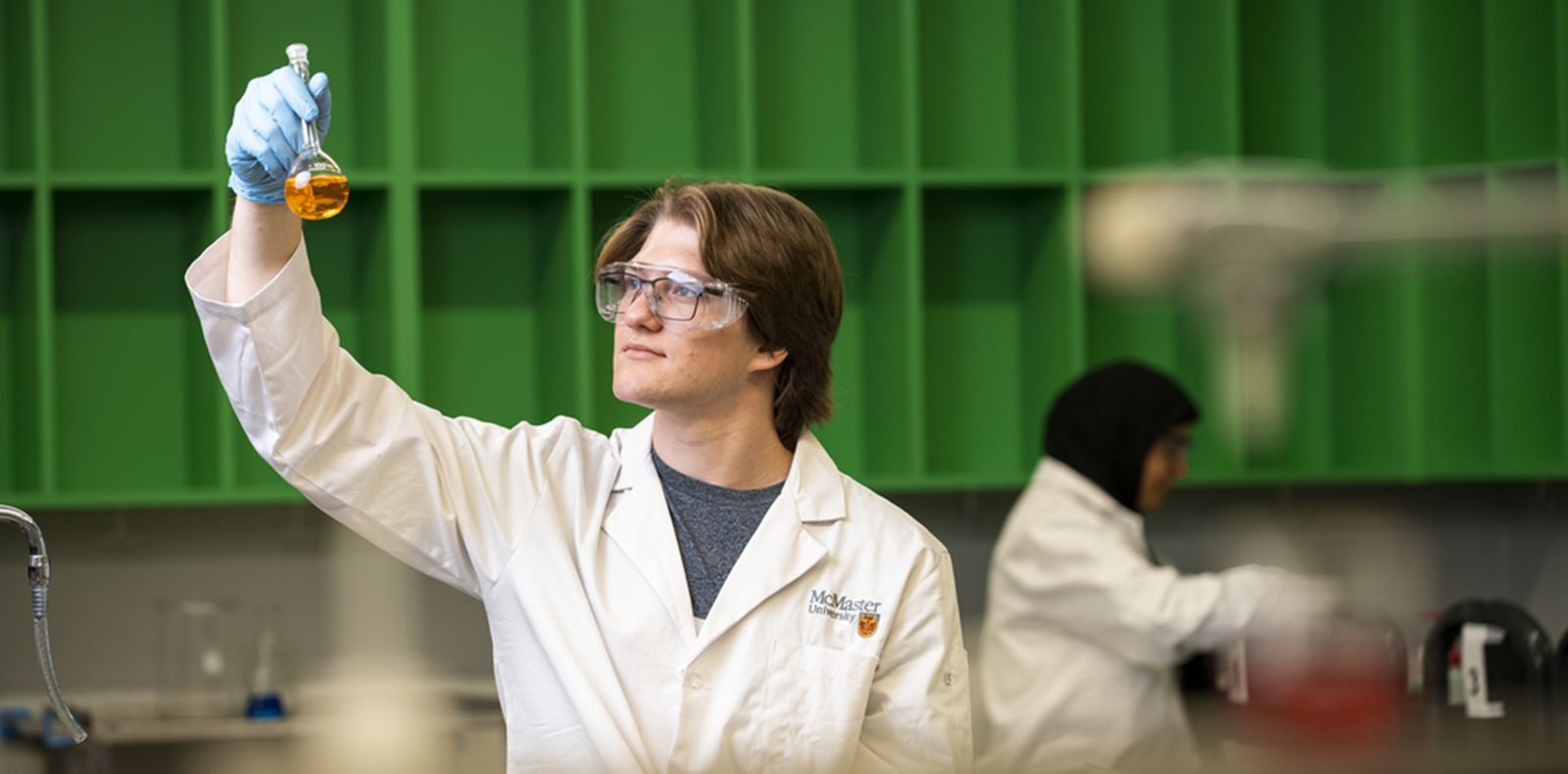 Person looking at a beaker with liquid in it