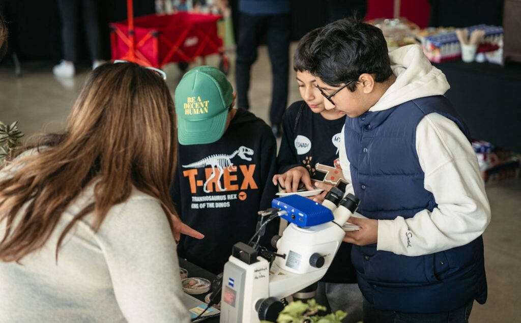 kids at a science experiment table at an event. 