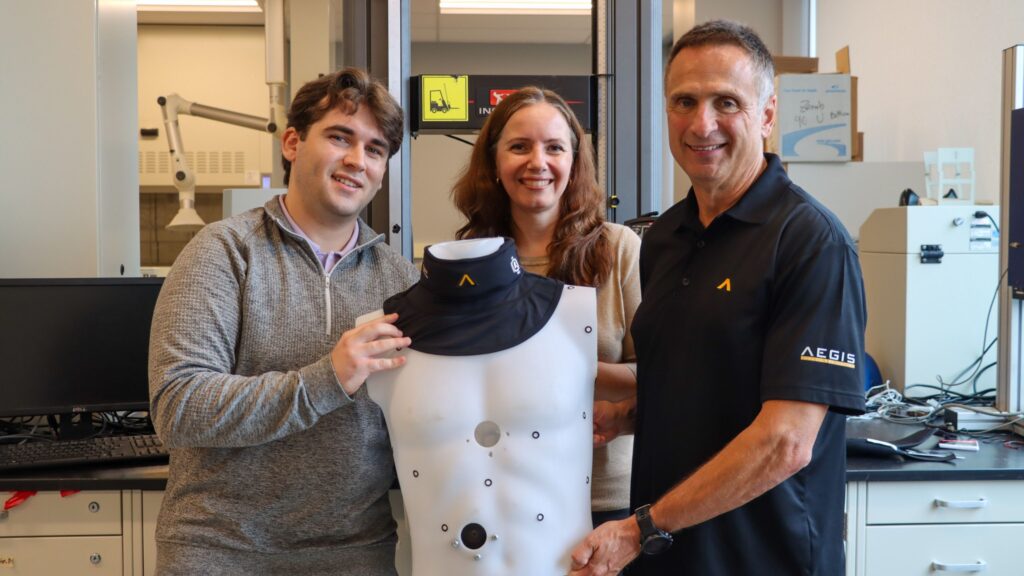 Carson Breweer, Cheryl Quenneville and Joe Camillo hold a mannequin torso that wears a hockey neck guard.